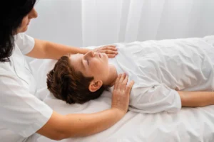 Female chiropractor providing shoulder pain relief treatment to young boy