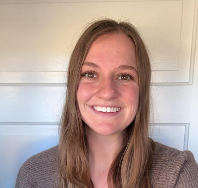 Tanner smiling in a casual indoor portrait wearing a brown sweater