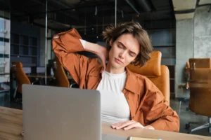 Woman working on laptop experiencing neck pain from poor posture